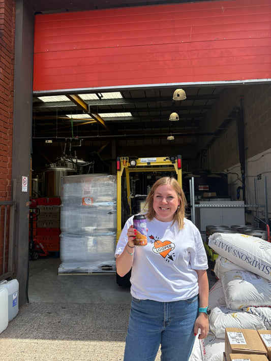 A female member of our team standing outside of gravity well brewery holding a can of our collab beer 