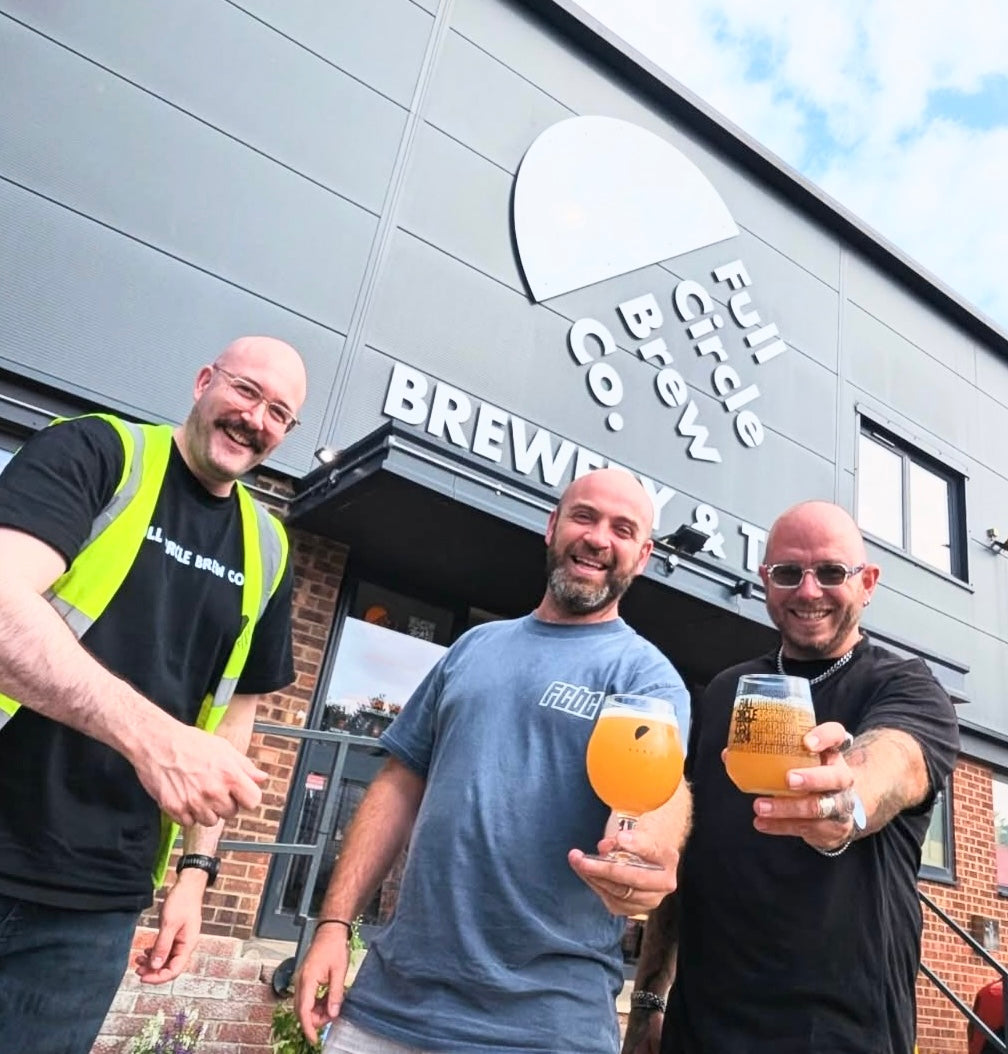 brewers holding beer outside of the full circle brewery
