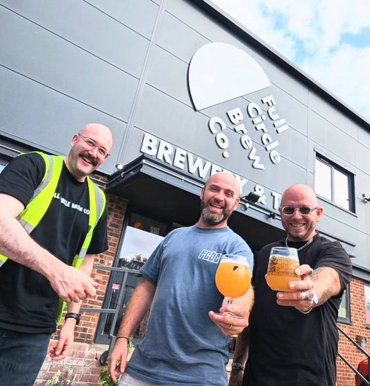 brewers holding beer outside of the full circle brewery