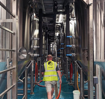 Brewer walking amongst brewing tanks