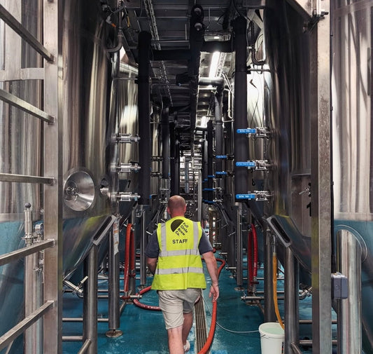 Brewer walking amongst brewing tanks