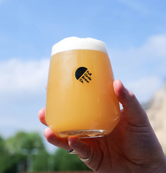 A schooner glass filled with a  Hazy Pale Ale called Rotator by Full Circle Brew Co 