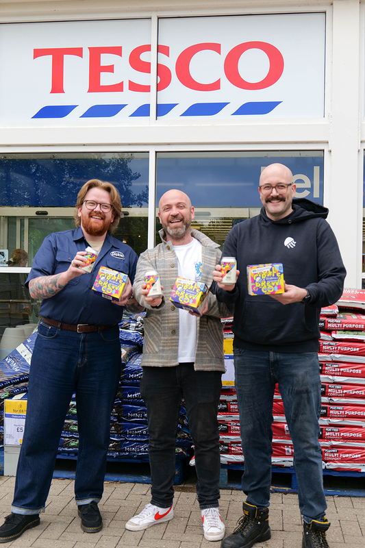 Three members of the Full Circle Brewery team stood outside Tesco holding cans and boxes of Hippy Jungle 