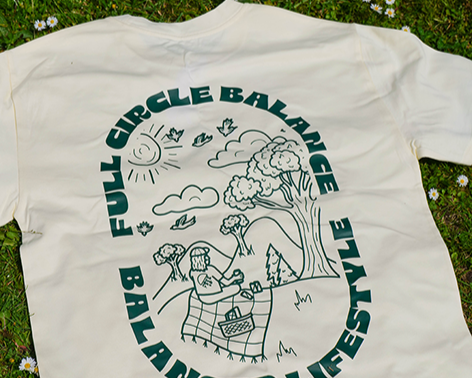 White t-shirt with green graphic design on grass