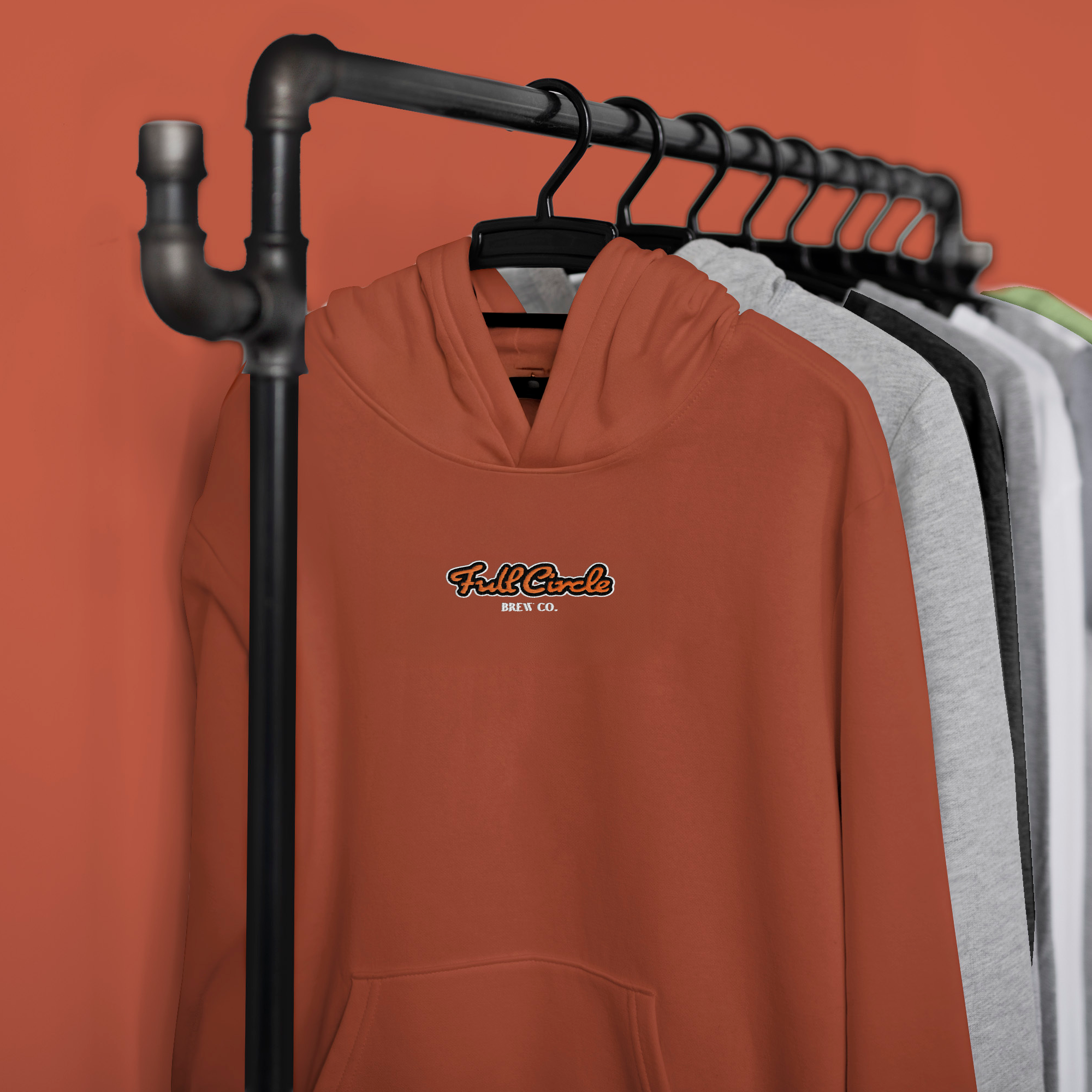 Brown hoodie with 'Full Circle' logo on a rack against an orange background